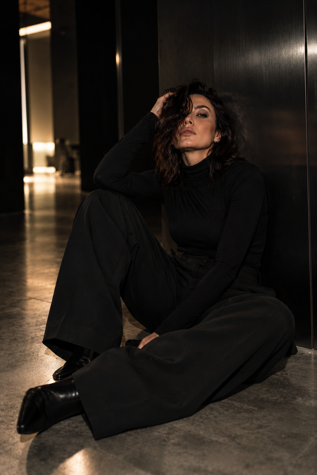Vanessa Döpp in schwarzem Look sitzt in modernem dunklen Interieur